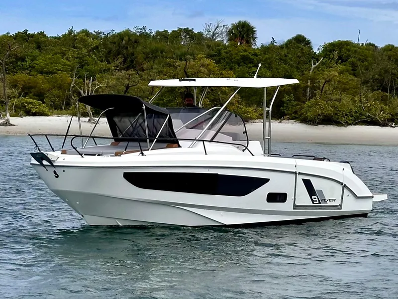 Slide: The Image of 2023 Beneteau Flyer 9 SUNdeck boat on water near a lush, green shoreline. - 6