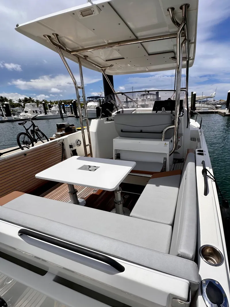 Slide: The Image of 2023 Beneteau Flyer 9 SUNdeck boat interior with seating and table, docked at marina. - 7