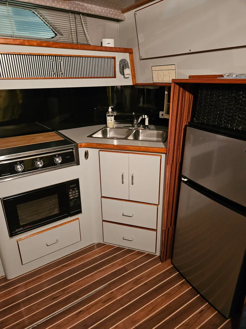 Slide: The Image of 1989 Sea Ray 390 Express yacht kitchen with stove, sink, and refrigerator. - 17