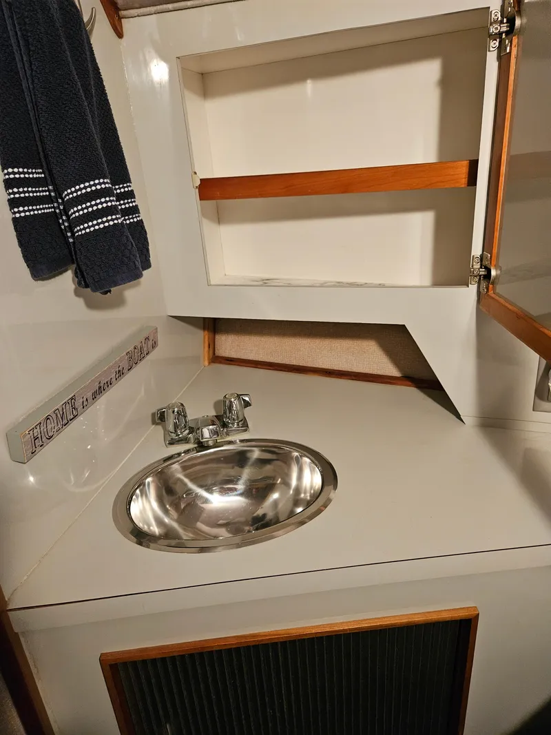 Slide: The Image of 1989 Sea Ray 390 Express bathroom sink with open cabinet and towel. - 22