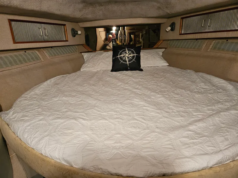 Slide: The Image of 1989 Sea Ray 390 Express cabin with round bed and nautical-themed pillow. - 23