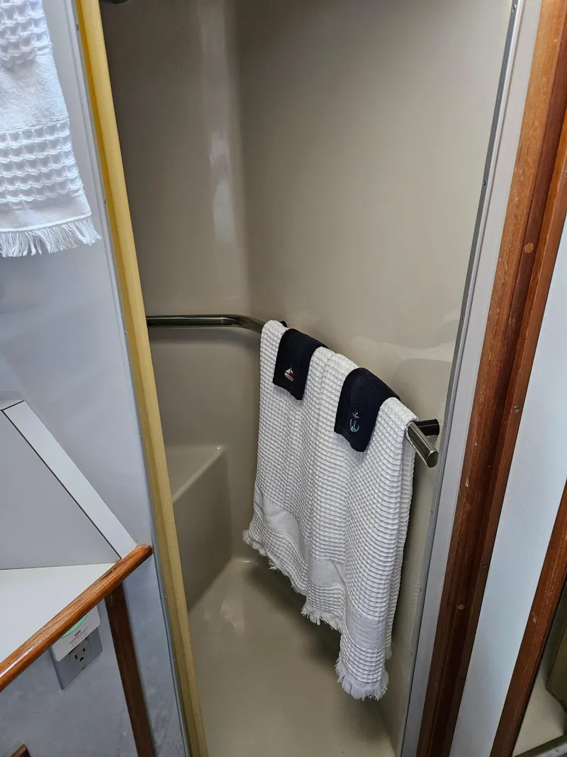 Slide: The Image of 1989 Sea Ray 390 Express shower area with white towels and wooden accents. - 30