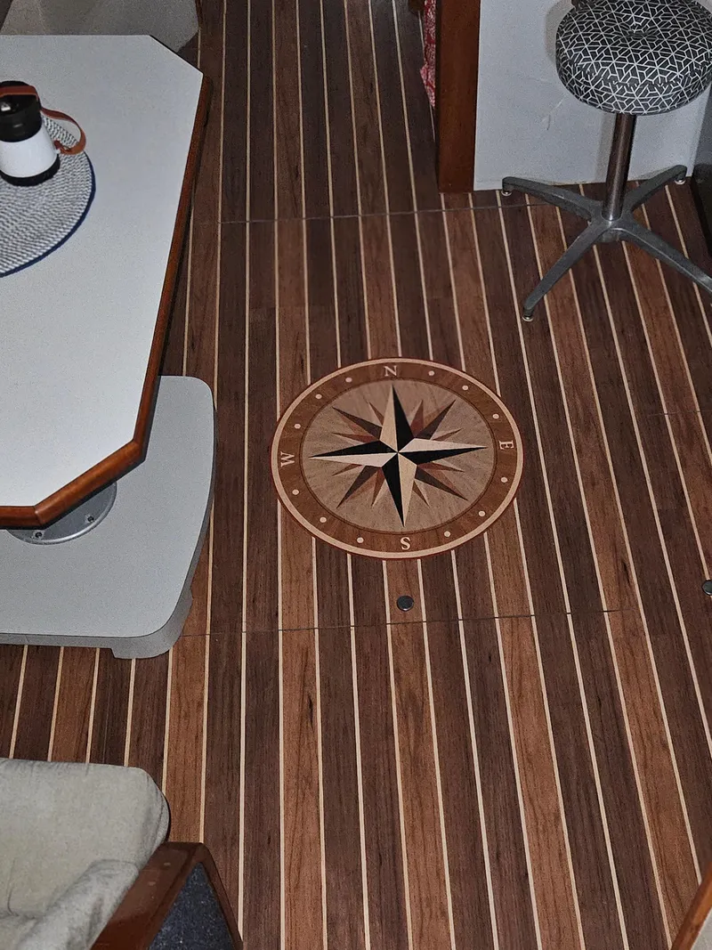 Slide: The Image of 1989 Sea Ray 390 Express interior with compass rose design on wooden floor. - 34