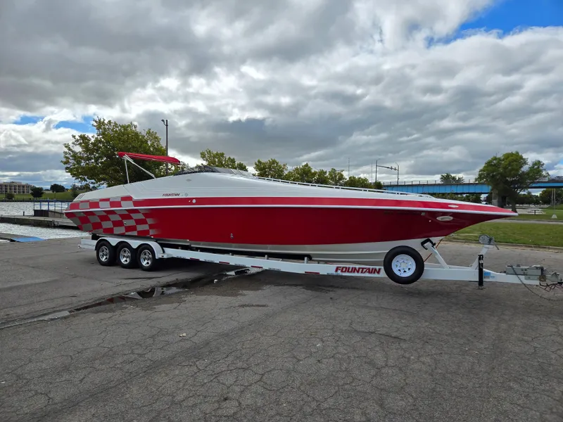 Slide: The Image of 1995 Fountain 38 Sport Cruiser, red and white, on a trailer under cloudy skies. - 3