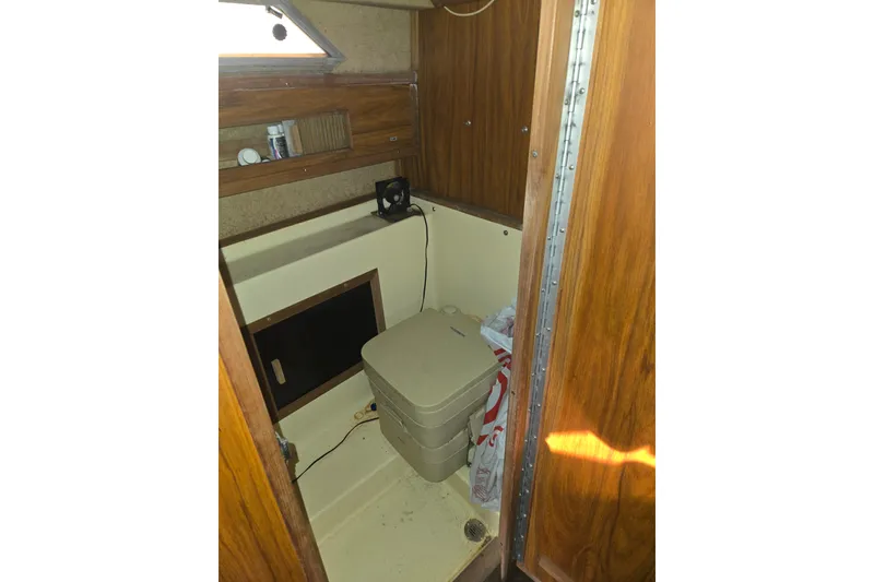 Slide: The Image of 1983 Sea Ray Weekender cabin interior with compact toilet and wooden cabinetry. - 12
