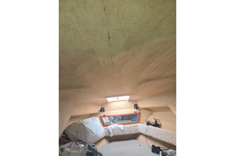 Slide: The Image of Interior cabin of 1983 Sea Ray Weekender boat, featuring beige upholstery and a small window. - 13