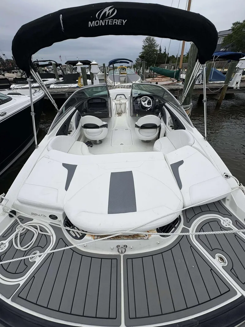 Slide: The Image of 2015 Monterey 224FS boat with sleek seating and stylish deck at a marina. - 4