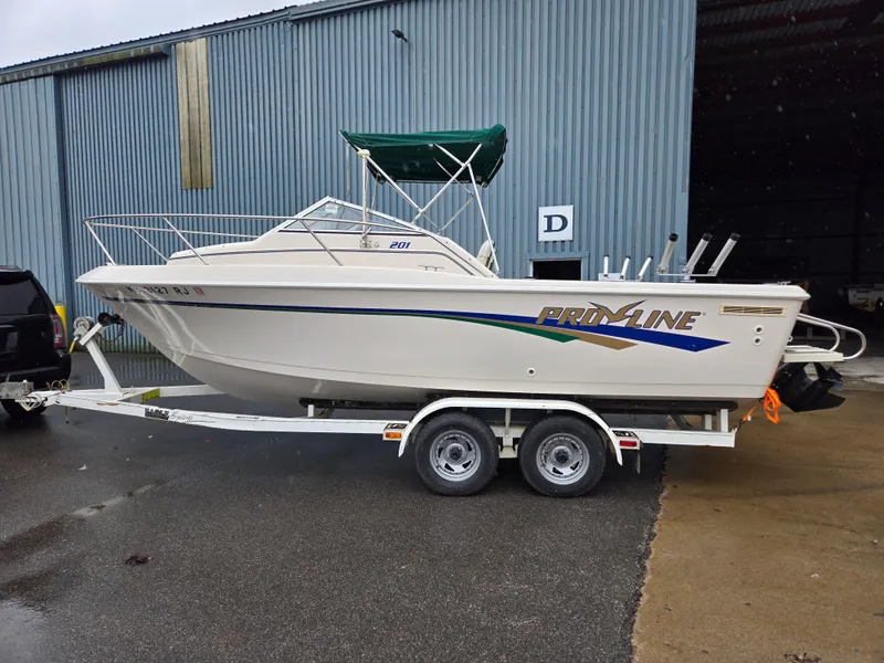 Slide: The Image of 1997 Pro-Line 201 Walkaround boat on trailer, parked outside a warehouse. - 1