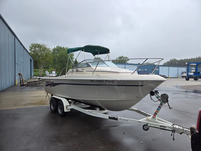 Slide: The Image of 1997 Pro-Line 201 Walkaround boat on trailer, parked outdoors on a rainy day. - 13