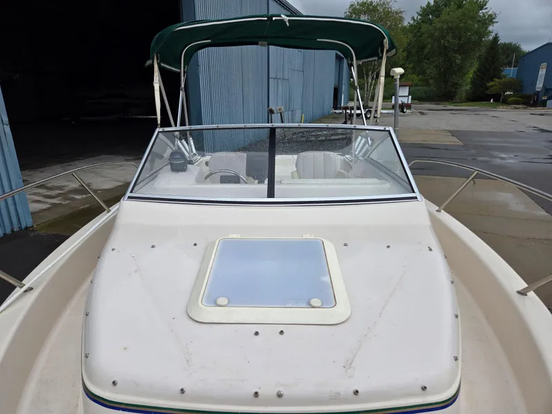 Slide: The Image of 1997 Pro-Line 201 Walkaround boat with green canopy, docked near blue warehouse. - 15