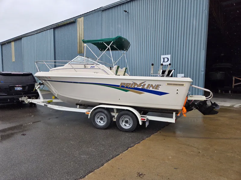 Slide: The Image of 1997 Pro-Line 201 Walkaround boat on trailer, parked outside a warehouse. - 2