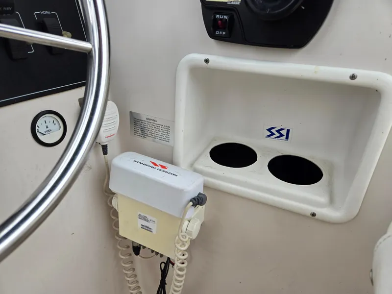 Slide: The Image of 1997 Pro-Line 201 Walkaround boat dashboard with steering wheel and communication equipment. - 24