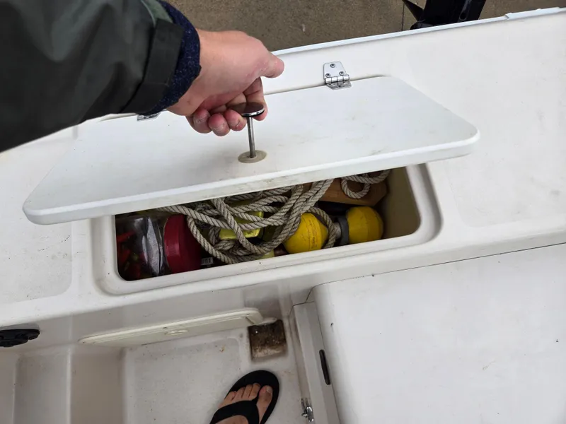 Slide: The Image of Person opening storage compartment on 1997 Pro-Line 201 Walkaround boat, revealing ropes and buoys. - 32
