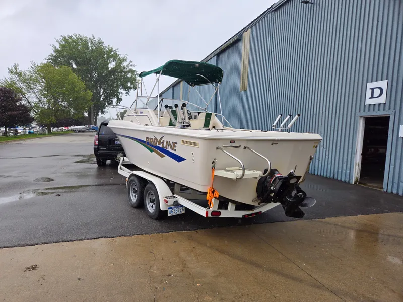 Slide: The Image of 1997 Pro-Line 201 Walkaround boat on trailer near a metal building. - 4