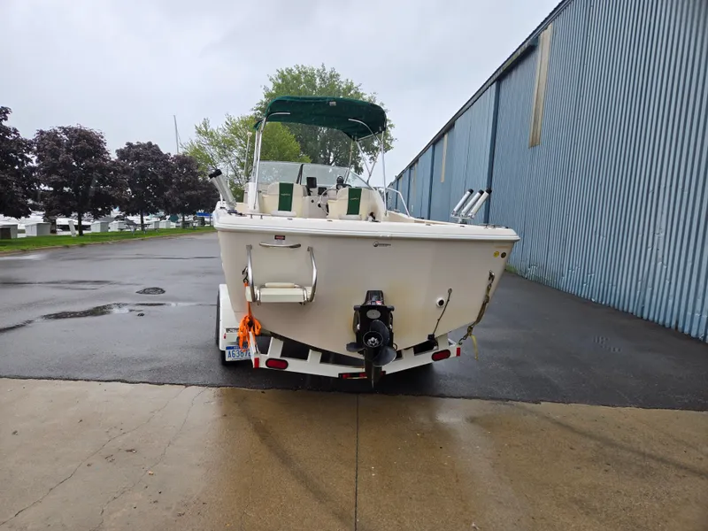 Slide: The Image of 1997 Pro-Line 201 Walkaround boat on trailer, parked near a blue warehouse. - 5