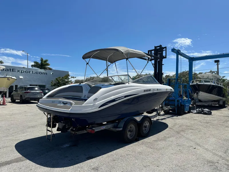 The Image of 2011 Yamaha SX210 boat on trailer at dealership under clear blue sky. - 0