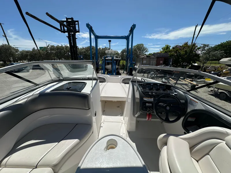 Slide: The Image of 2011 Yamaha Boats SX210 interior with steering wheel and seating, parked outdoors. - 2