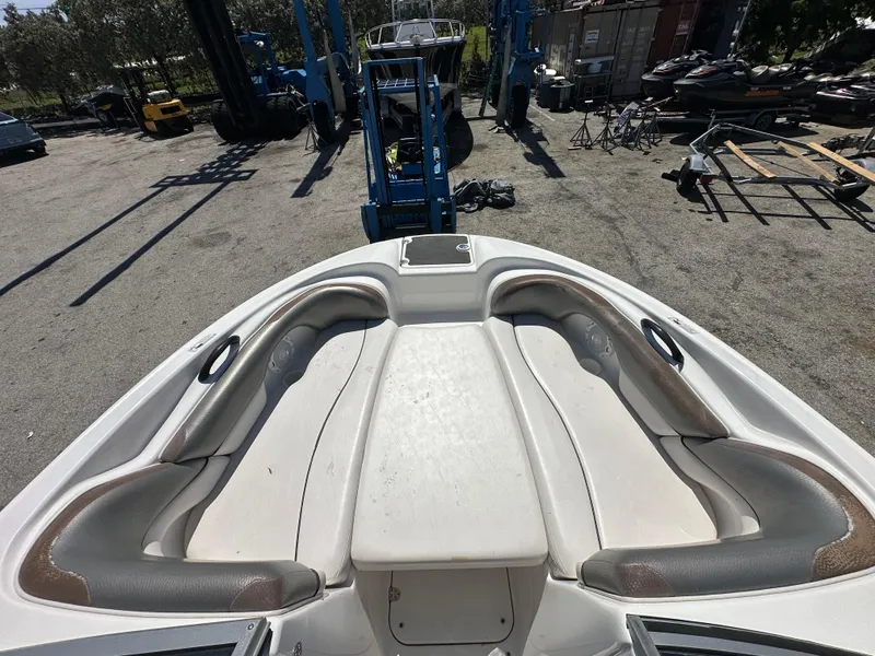 Slide: The Image of 2011 Yamaha Boats SX210 bow seating area in a boatyard setting. - 25