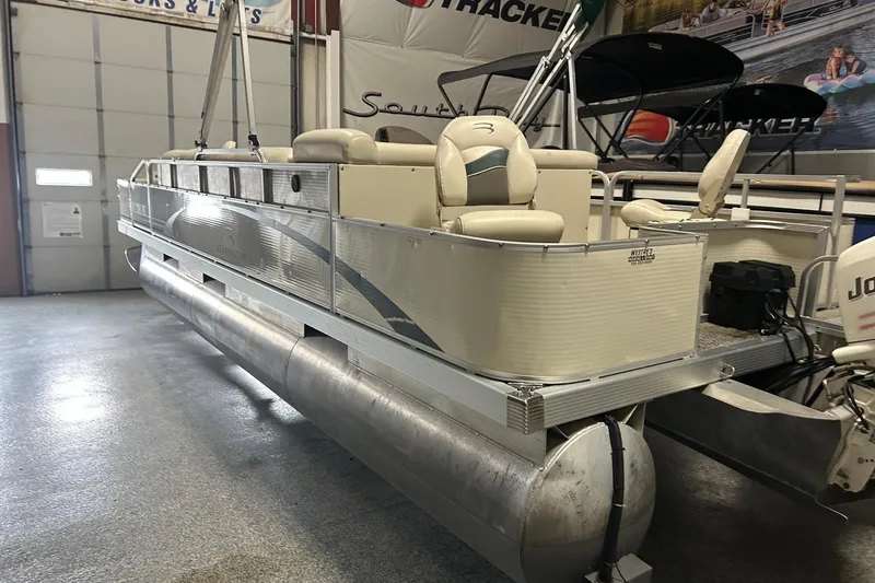 Slide: The Image of 2005 Bennington II 227FSi pontoon boat in showroom, featuring beige seating and aluminum pontoons. - 3