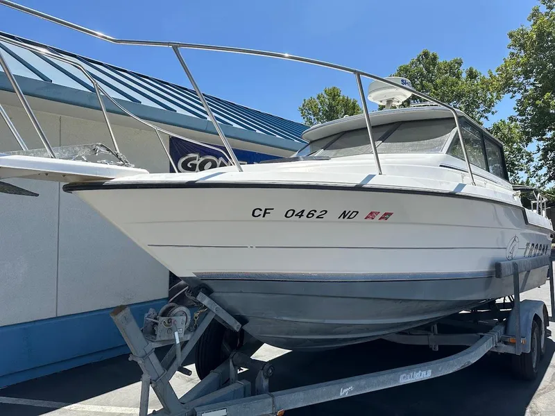 Slide: The Image of 1992 Bayliner 2359 Trophy boat on trailer, parked outdoors under clear blue sky. - 6
