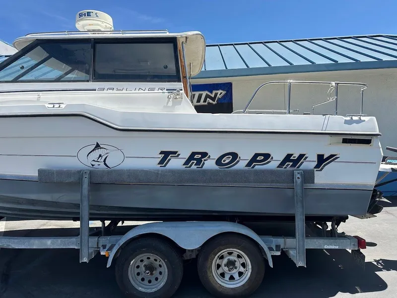 Slide: The Image of 1992 Bayliner 2359 Trophy boat on trailer, side view, with clear blue sky background. - 7