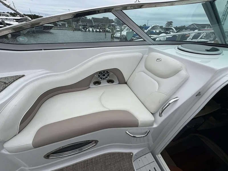 Slide: The Image of 2018 Crownline 264 CR boat interior with white and beige seating, dockside view. - 10