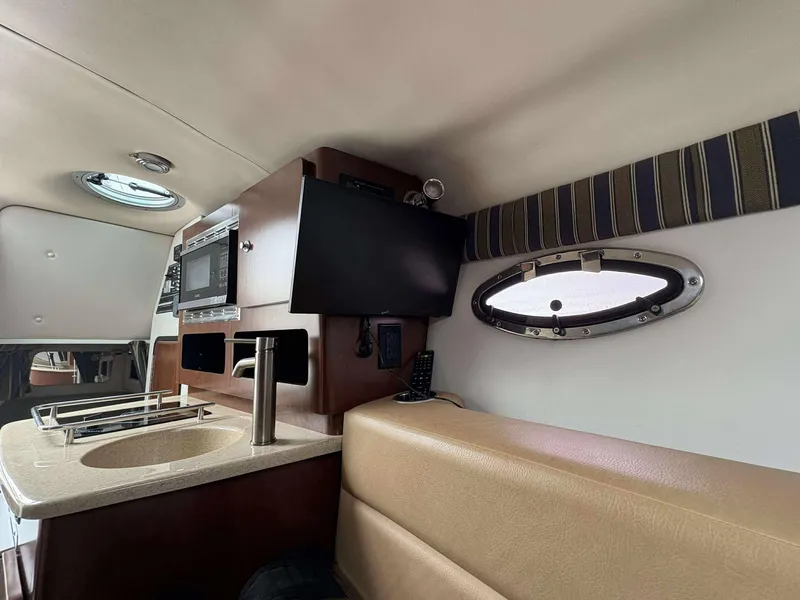 Slide: The Image of Interior of 2018 Crownline 264 CR boat with kitchenette and porthole window. - 16