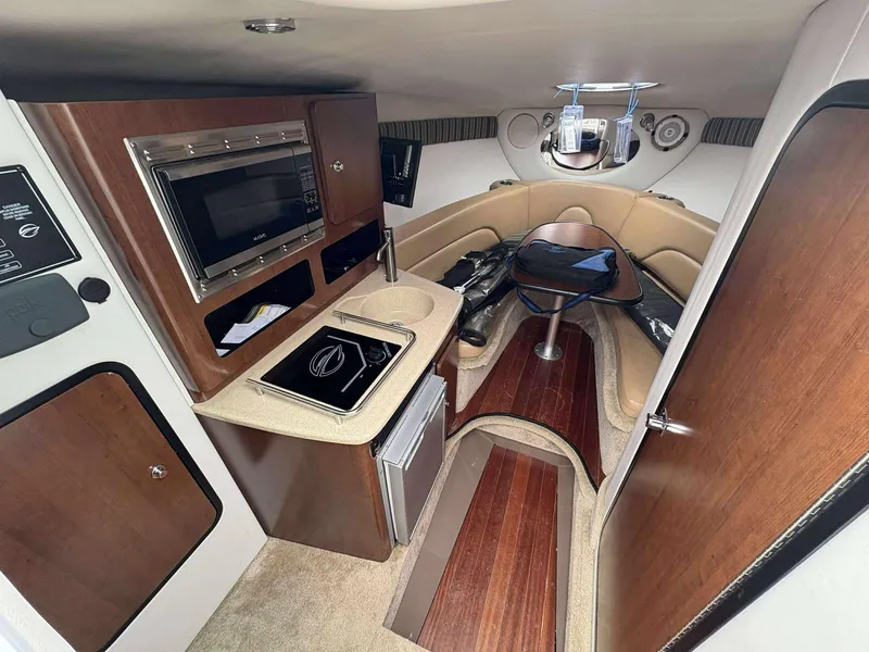 Slide: The Image of 2018 Crownline 264 CR cabin interior with kitchenette, seating, and wood accents. - 21