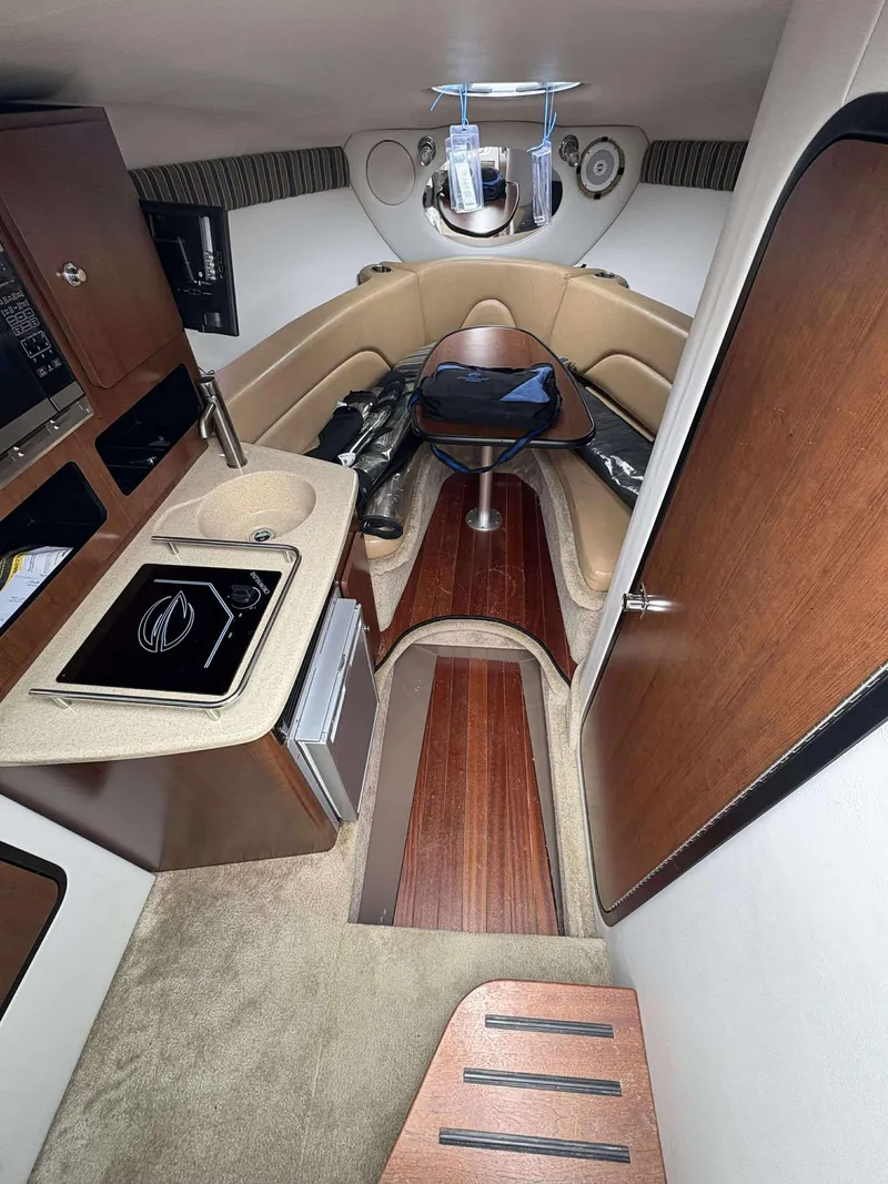 Slide: The Image of 2018 Crownline 264 CR cabin interior with kitchenette, seating, and wood accents. - 22