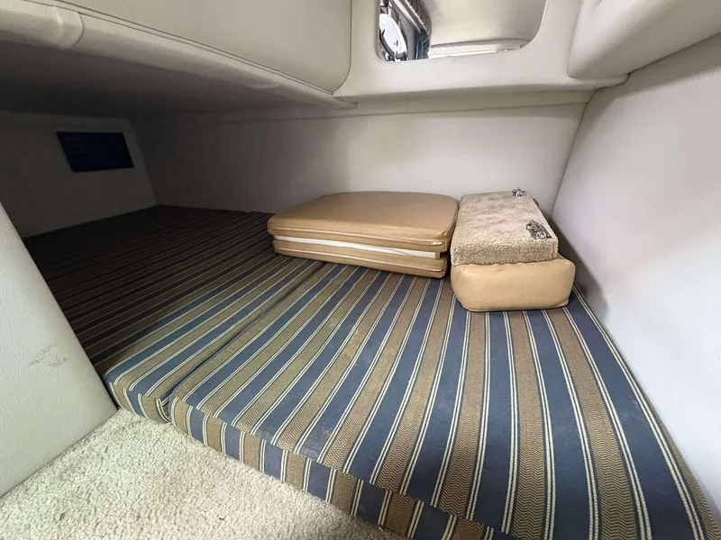 Slide: The Image of 2018 Crownline 264 CR cabin interior with striped cushions and beige accents. - 24