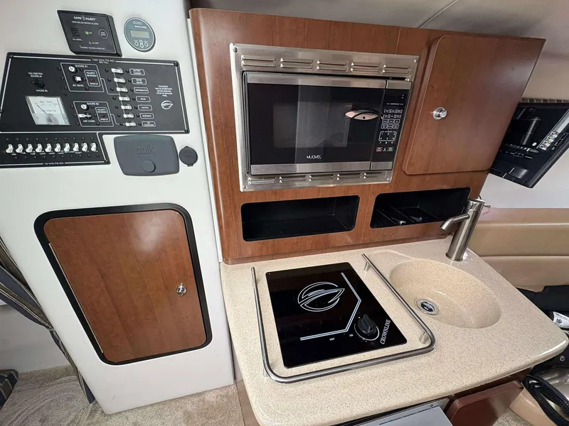 Slide: The Image of 2018 Crownline 264 CR boat interior with kitchenette, featuring microwave, sink, and control panel. - 25