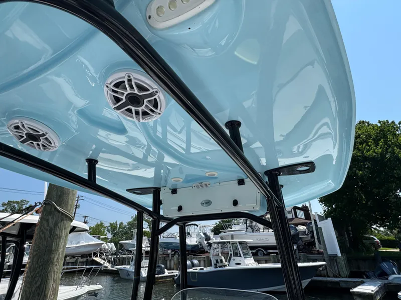 Slide: The Image of 2022 Tidewater 220 LXF boat with blue T-top and speakers at a marina. - 14