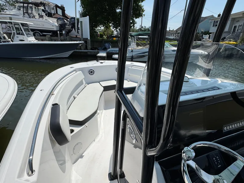 Slide: The Image of 2022 Tidewater 220 LXF boat interior with seating and steering wheel at a marina. - 6