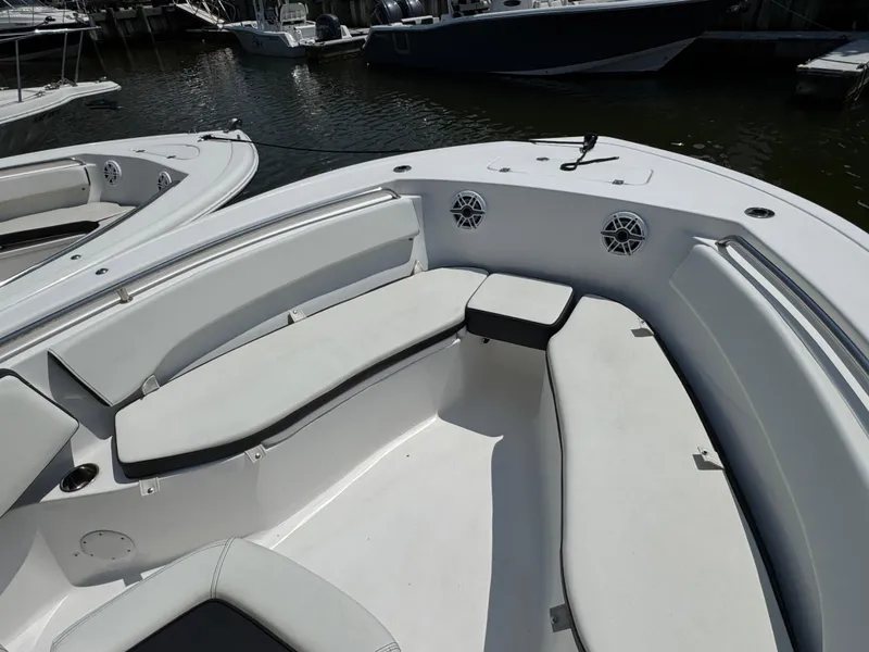 Slide: The Image of 2022 Tidewater 220 LXF boat interior with cushioned seating and speakers, docked at marina. - 8