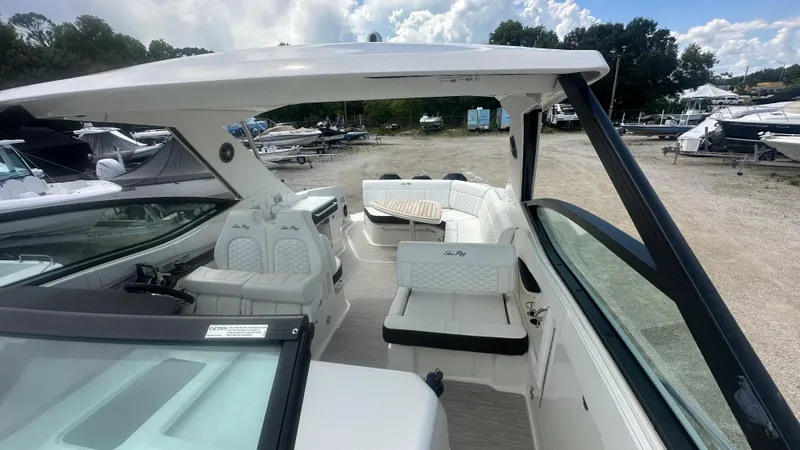 Slide: The Image of 2023 Sea Ray Sundancer 320 Outboard boat interior with seating and table, docked outdoors. - 6