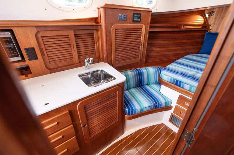 Slide: The Image of 2015 Hinckley Picnic Boat 37 MKIII interior with wood cabinetry, sink, and striped seating. - 31