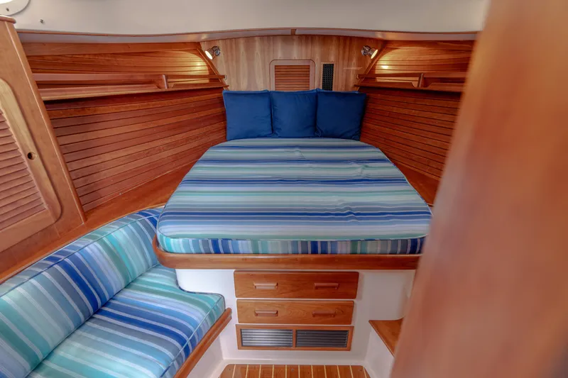 Slide: The Image of 2015 Hinckley Picnic Boat 37 MKIII cabin with striped bedding and wooden interior. - 32