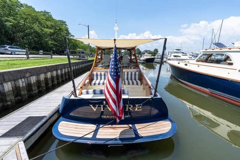 Slide: The Image of 2015 Hinckley Picnic Boat 37 MKIII docked with American flag, striped seating, and canopy. - 39