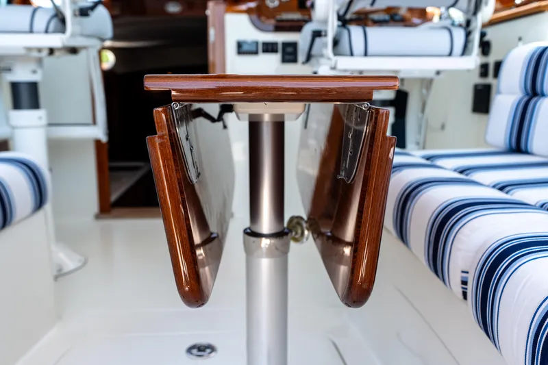 Slide: The Image of Interior of 2015 Hinckley Picnic Boat 37 MKIII with foldable wooden table and striped seating. - 41