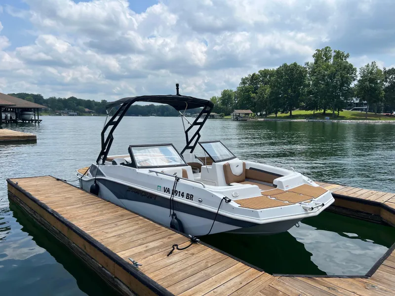 The Image of 2024 Starcraft SVX 210 IO boat docked on a serene lake under a cloudy sky. - 1