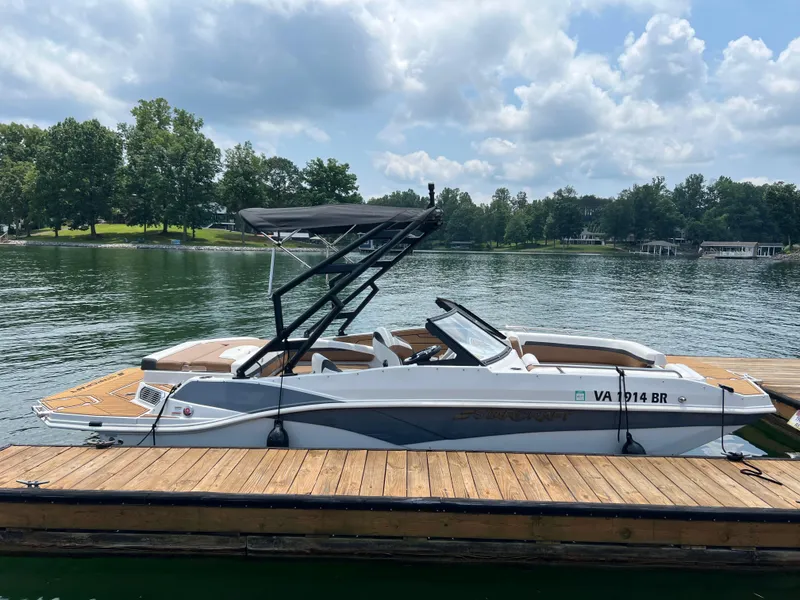 Slide: The Image of 2024 Starcraft SVX 210 IO boat docked on a serene lake under a cloudy sky. - 2
