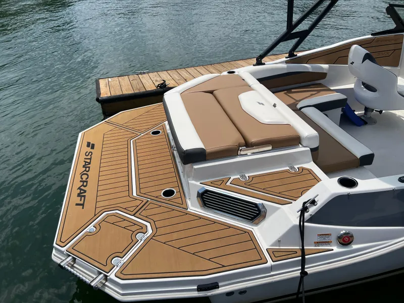 Slide: The Image of 2024 Starcraft SVX 210 IO boat with tan seating and deck, docked on calm water. - 3