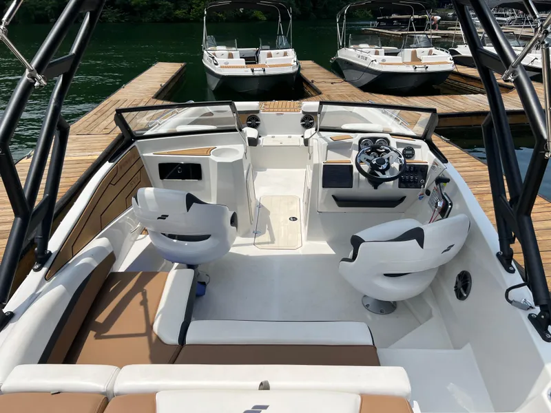 Slide: The Image of 2024 Starcraft SVX 210 IO boat interior with seating, steering wheel, and docked boats in background. - 4