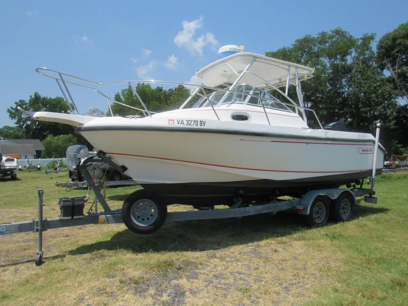 The Image of 1997 Boston Whaler 23 Conquest boat on trailer, parked on grassy area under clear sky. - 1