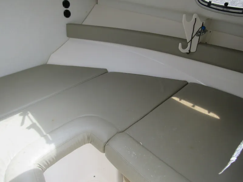 Slide: The Image of 1997 Boston Whaler 23 Conquest cabin interior with cushioned seating and storage. - 10