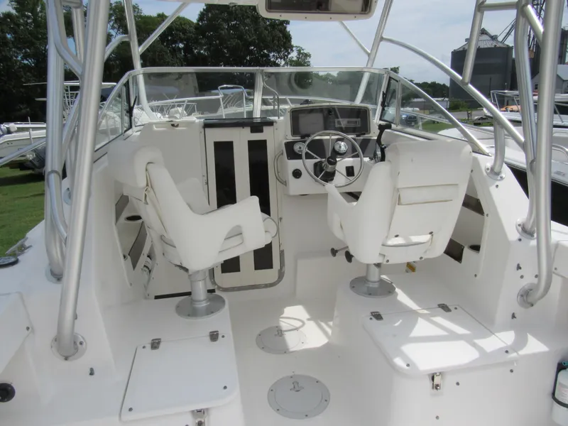 Slide: The Image of 1997 Boston Whaler 23 Conquest boat interior with dual white captain chairs and steering console. - 17