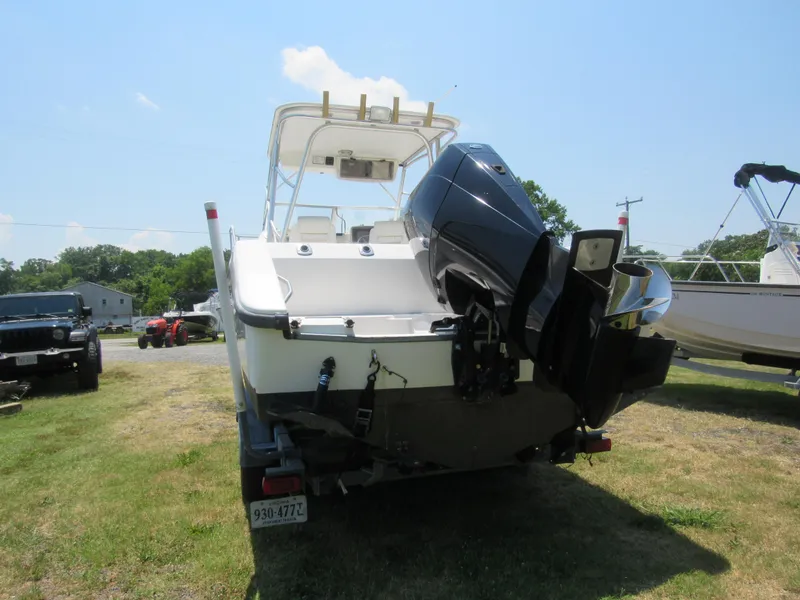 Slide: The Image of 1997 Boston Whaler 23 Conquest boat with outboard motor on trailer, parked outdoors. - 4