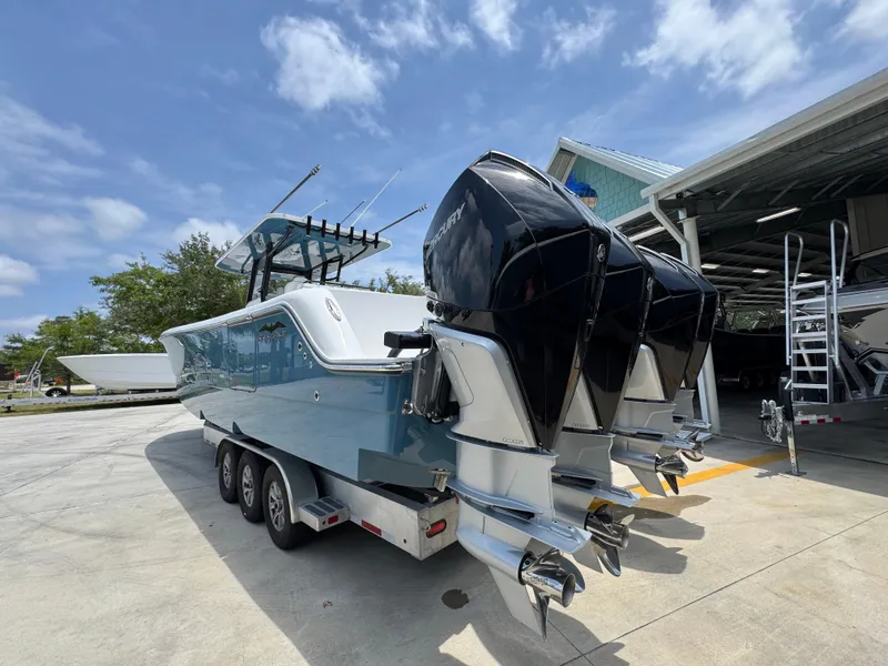 Slide: The Image of 2026 Invincible 36 Catamaran with triple outboard engines on a trailer, under a clear sky. - 16