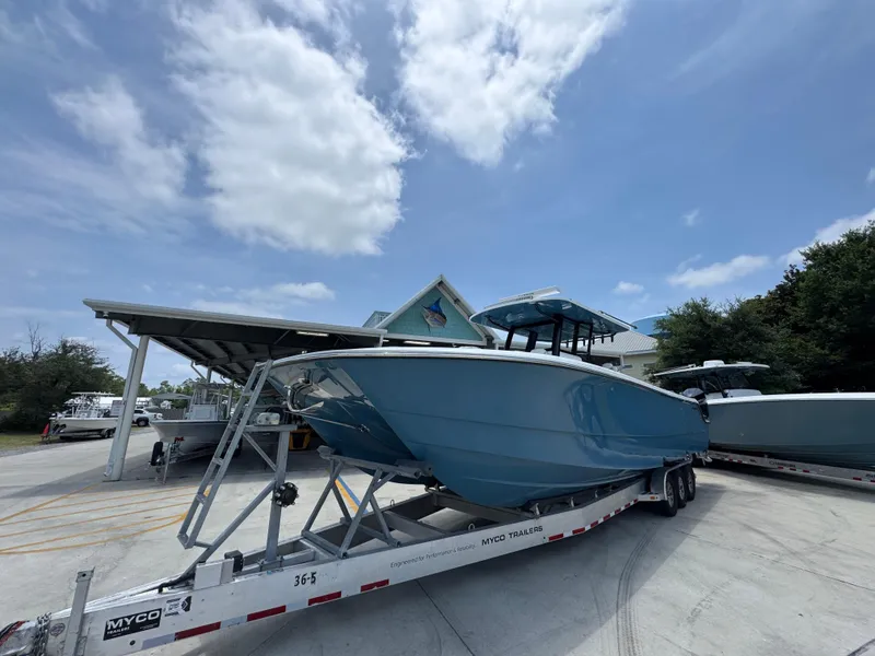 Slide: The Image of 2026 Invincible 36 Catamaran on trailer under blue sky, parked near building. - 4