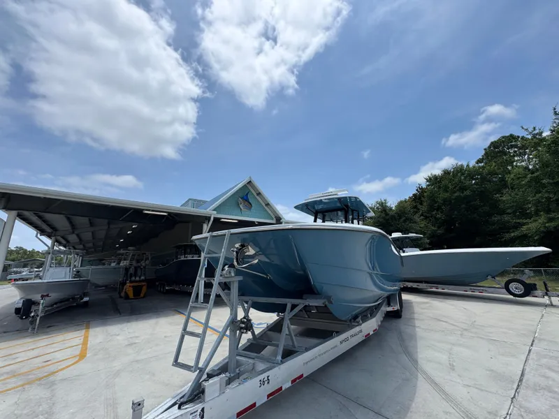 Slide: The Image of 2026 Invincible 36 Catamaran on trailer under blue sky, parked near a covered area. - 5